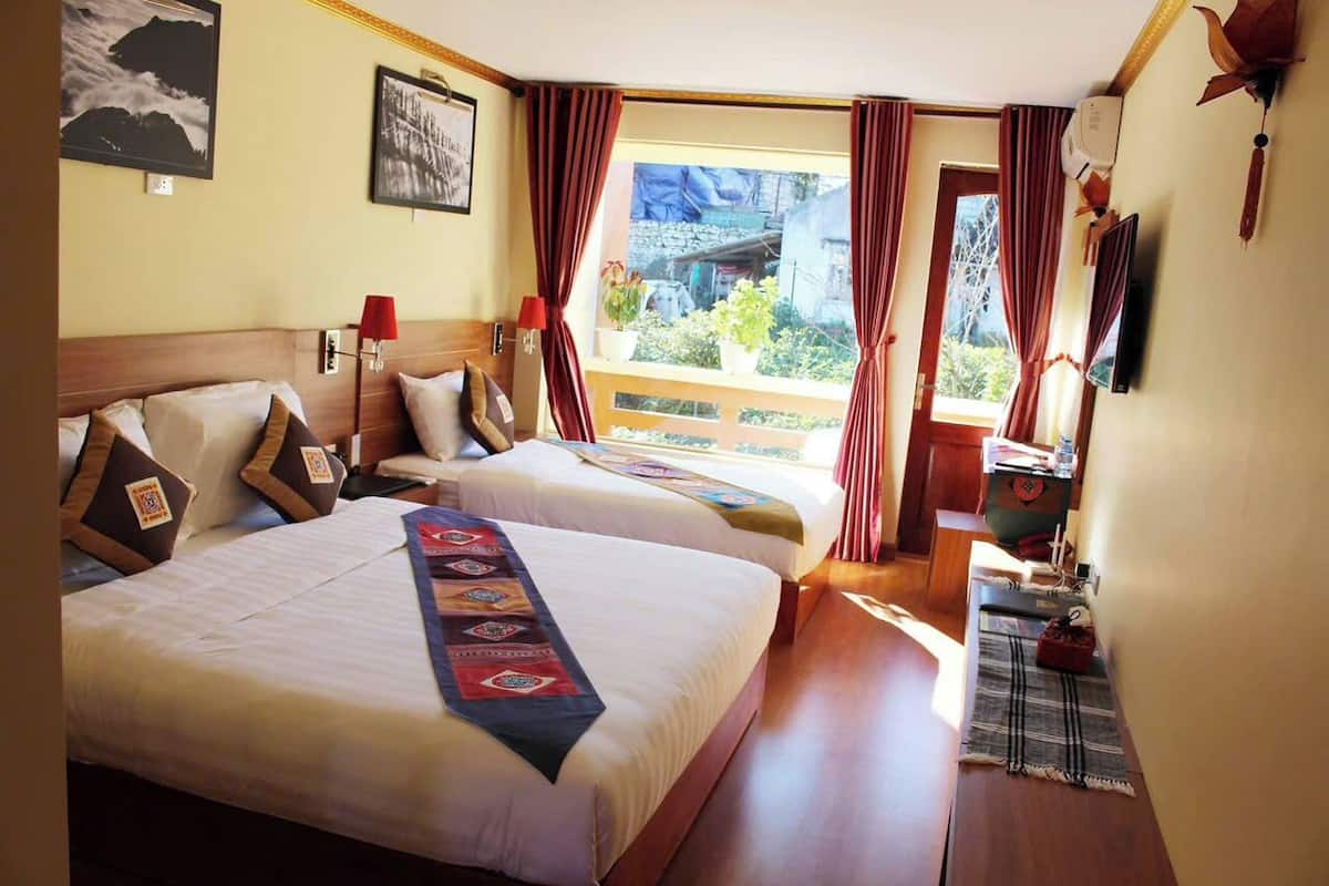 Habitación de hotel con dos camas, un balcón y una televisión.