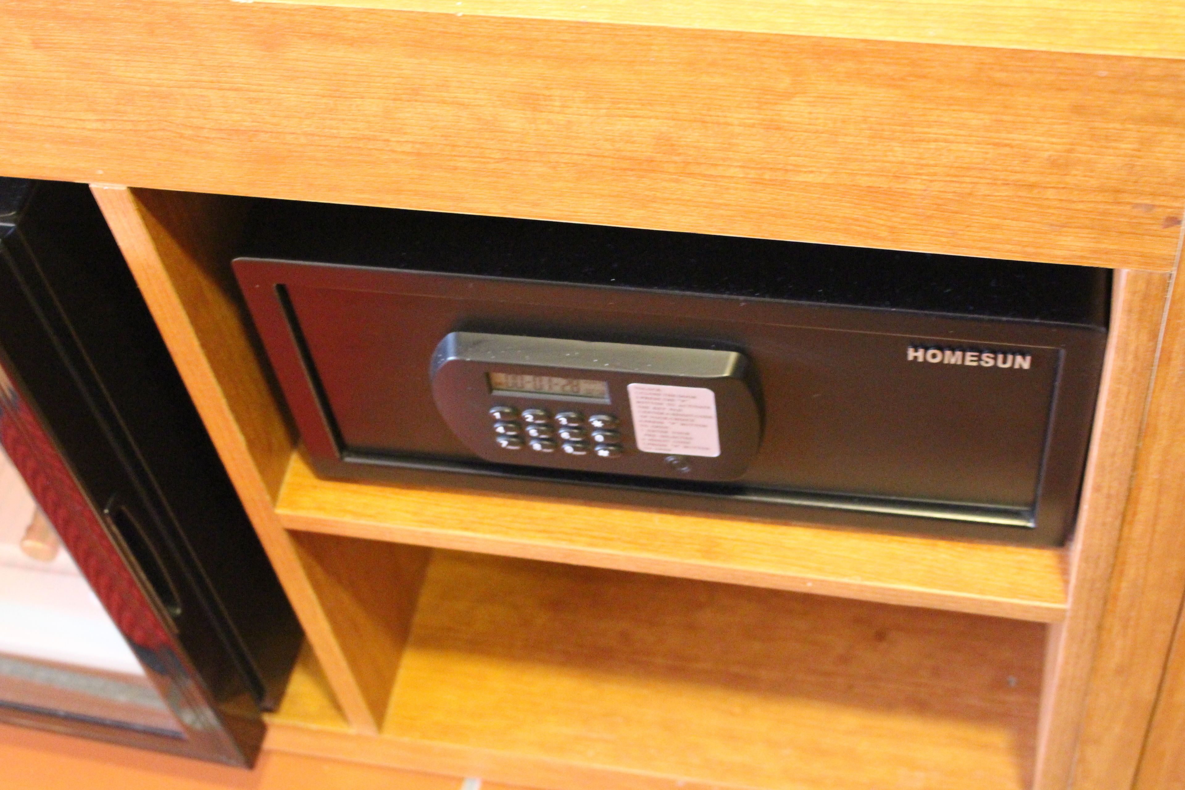 A secure electronic safe with a keypad, labeled "HOMESUN," in a wooden cabinet.