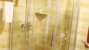 Un box de ducha con paredes de vidrio, interior de madera, un perchero y un estante pequeño.