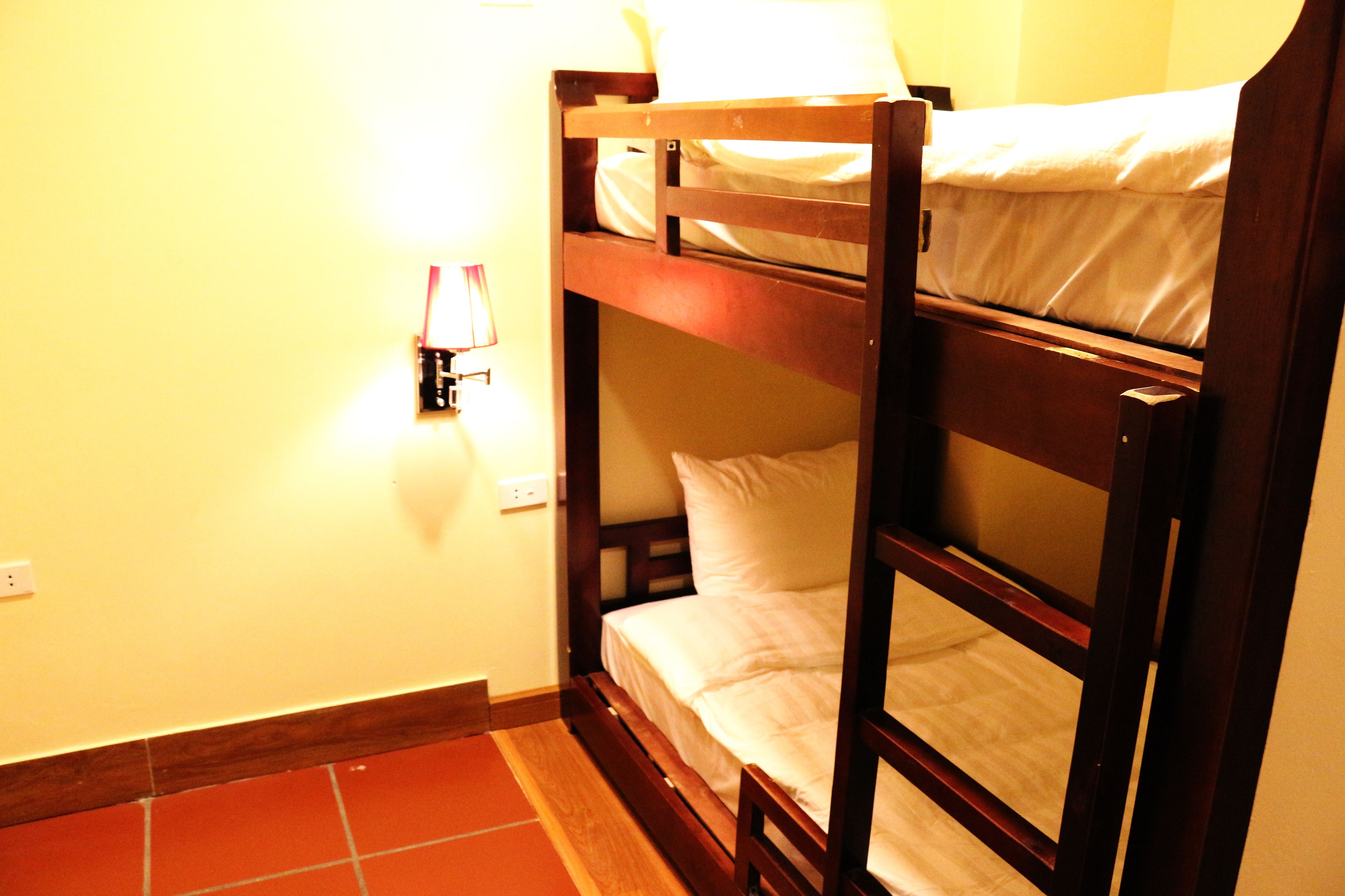 A bunk bed room with a nightstand and a lamp.