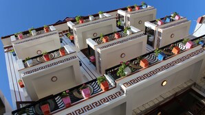 Hotel com várias varandas, cada uma decorada com vasos de plantas e detalhes decorativos.