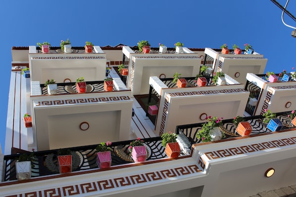 Un hotel con varios balcones, cada uno con un diseño geométrico y macetas con plantas.