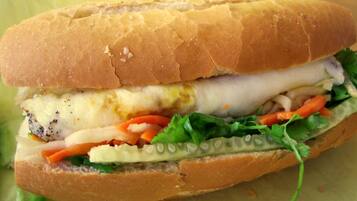 Un sándwich con pan crujiente, lechuga, tomate y un relleno blanco.