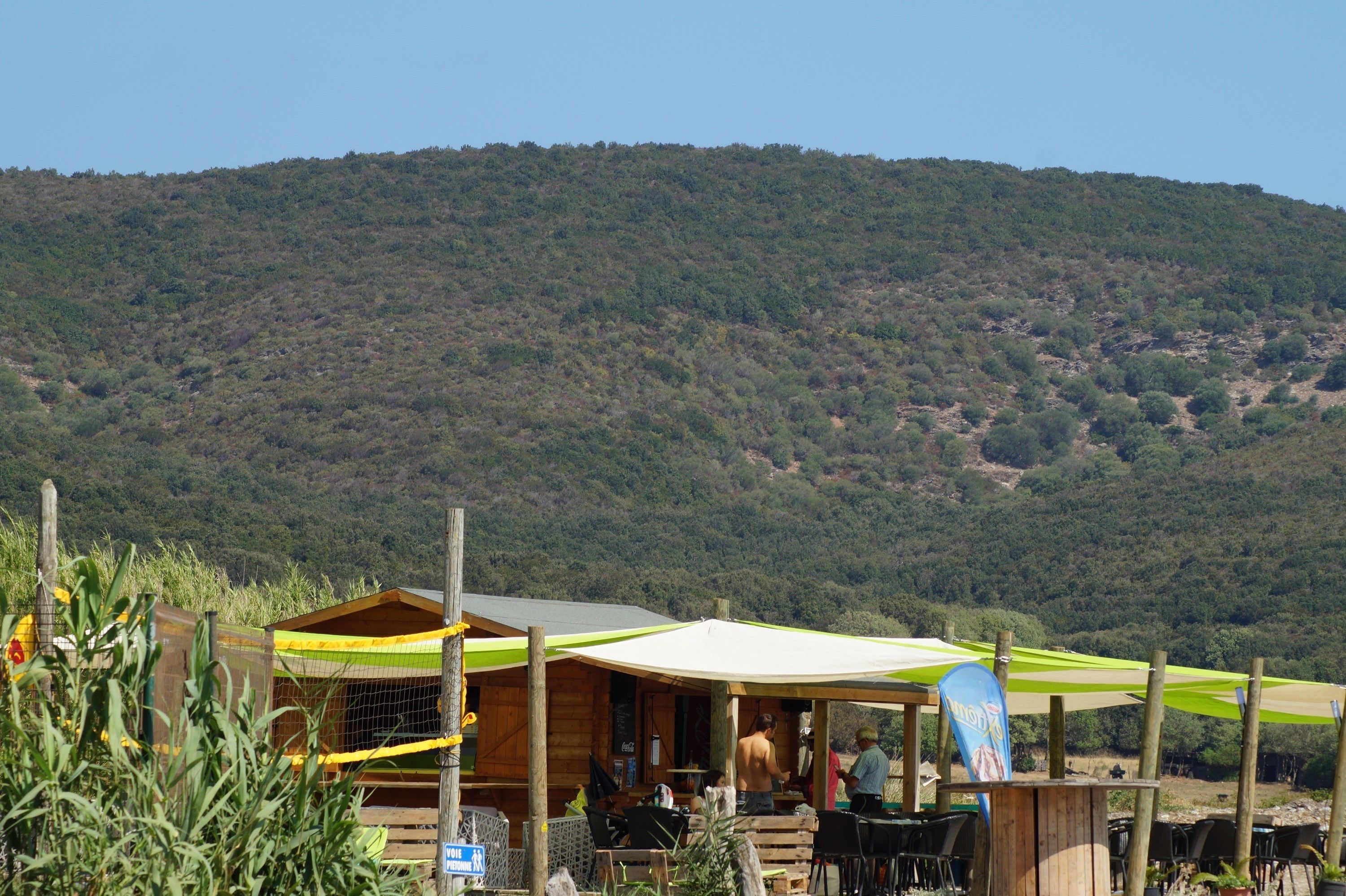 A rustic wooden cabin with outdoor seating and a view of a forested hill.