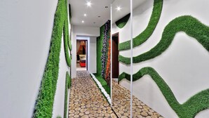 Un corridoio con pavimento decorato, dettagli murali verdi e uno specchio che riflette l'ambiente.