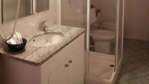 A bathroom with a sink, mirror, and glass-enclosed shower. - Hotel Laghetto (Frabosa Sottana)