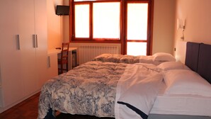 A bedroom with a bed, a desk, a chair, and a TV on the wall. - Hotel Laghetto (Frabosa Sottana)