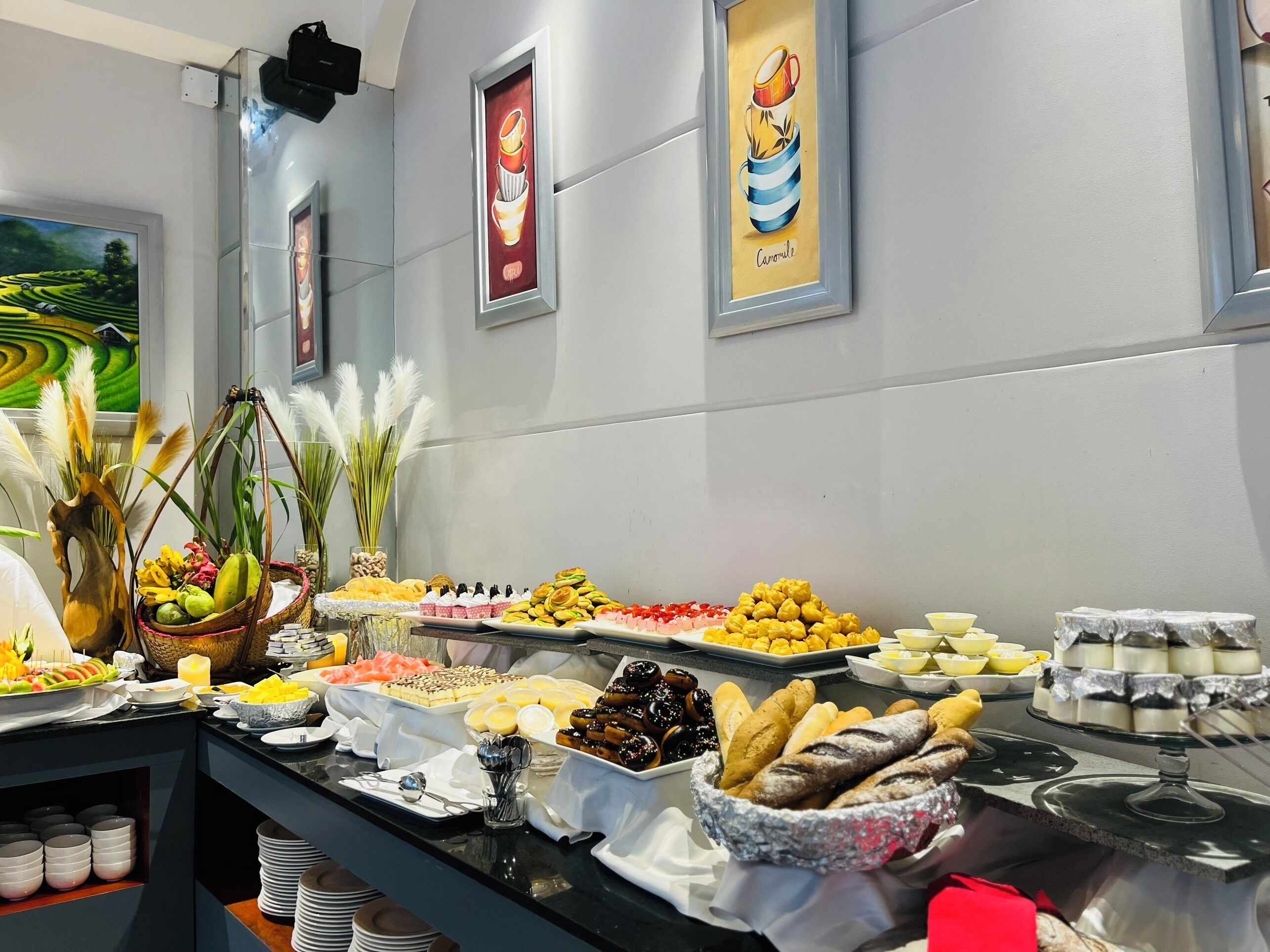 A buffet with various food items and a painting of a landscape.