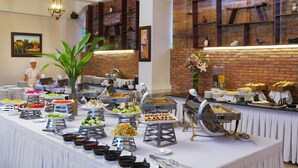 A buffet setup with various food stations and a brick wall in the background. - Phu Quoc Ocean Pearl Hotel (Phu Quoc)