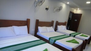A hotel room with four single beds, each with a wooden headboard and white bedding. There are wall-mounted fans and a door visible. - Marany Guesthouse (Kampot)