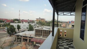 A balcony with a checkered floor, overlooking a construction site and surrounding buildings. - Marany Guesthouse (Kampot)