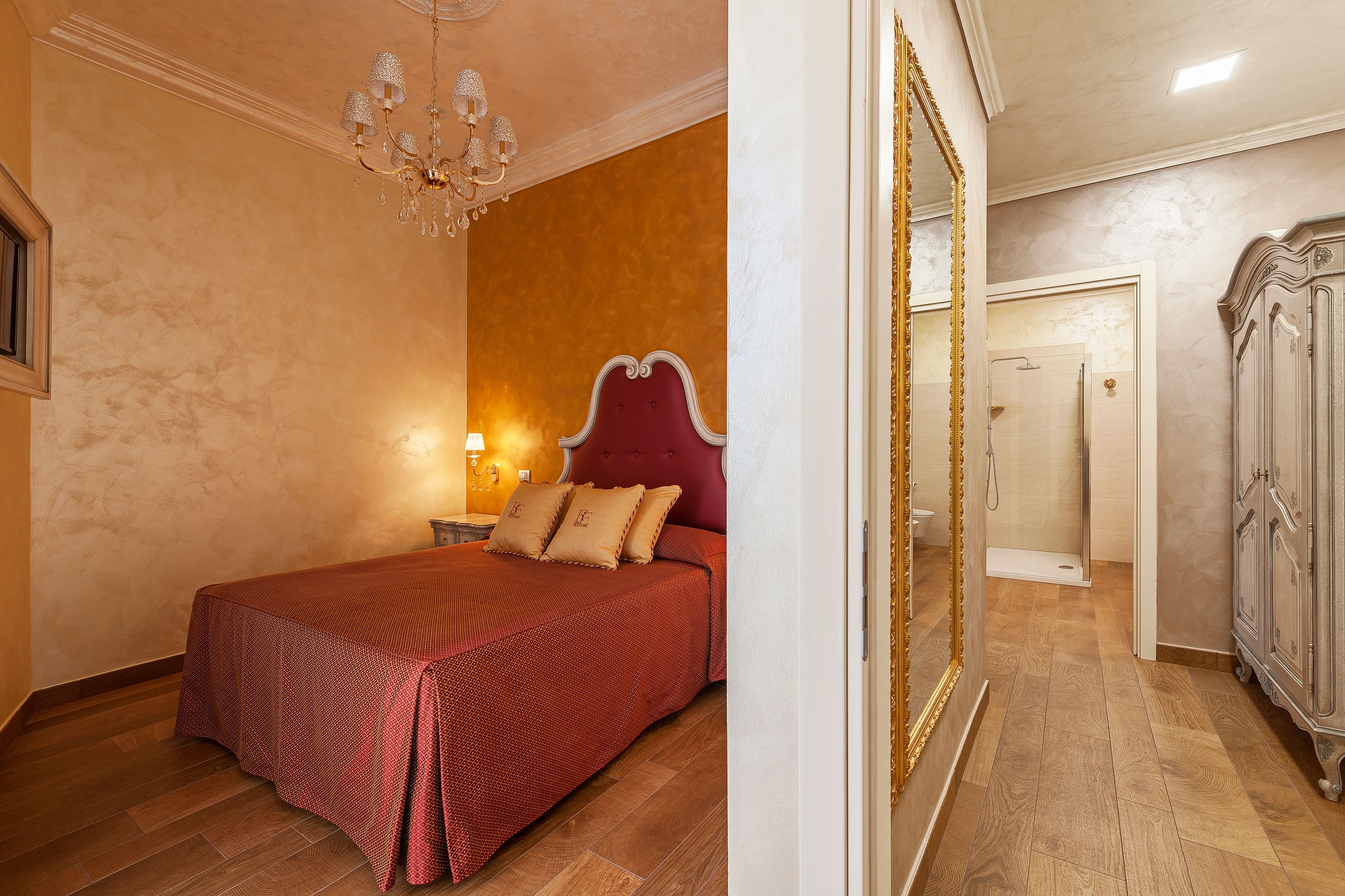 A bedroom with a large bed, a chandelier, and a wardrobe.