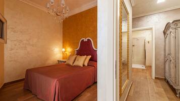 A bedroom with a large bed, a chandelier, and a wardrobe.