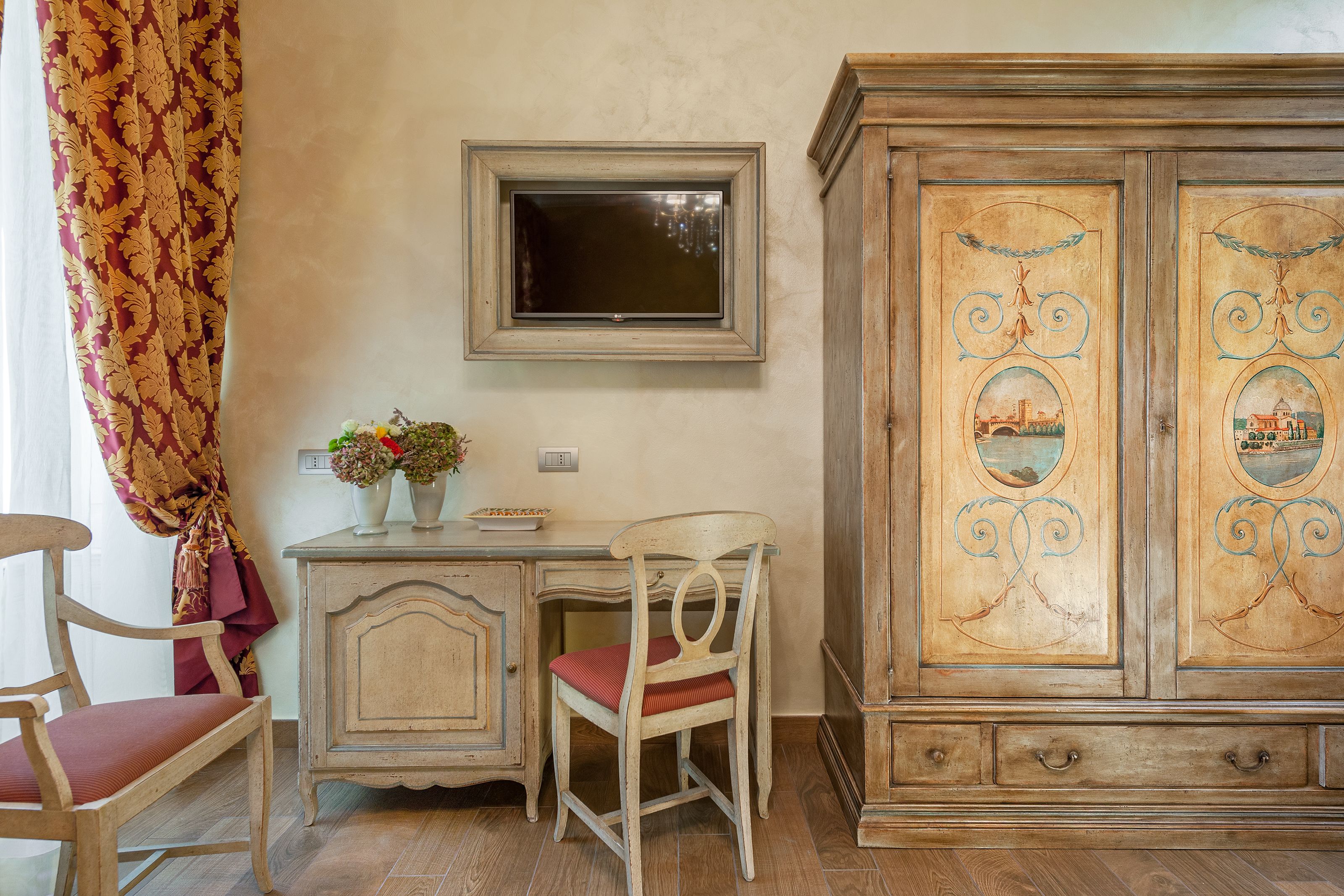 Une pièce comprenant un bureau en bois, une chaise, un téléviseur fixé au mur et un meuble avec des panneaux décoratifs.