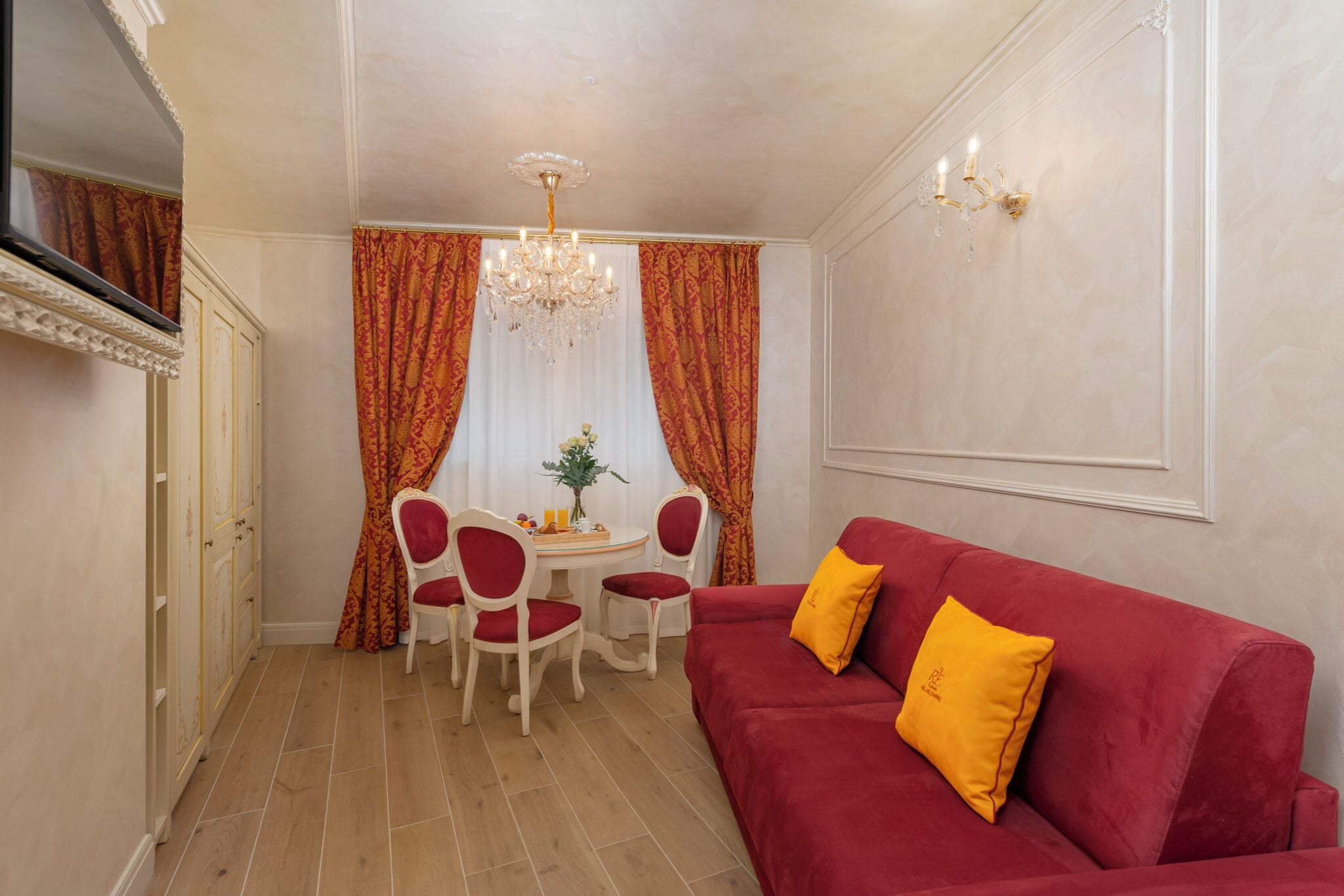 Ein Essbereich mit einer roten Couch, einem Chandelier und einem Tisch mit Stühlen.