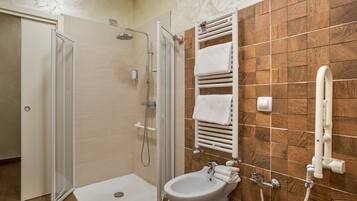 A bathroom with a glass-enclosed shower, a white sink, and a wooden-tiled wall.