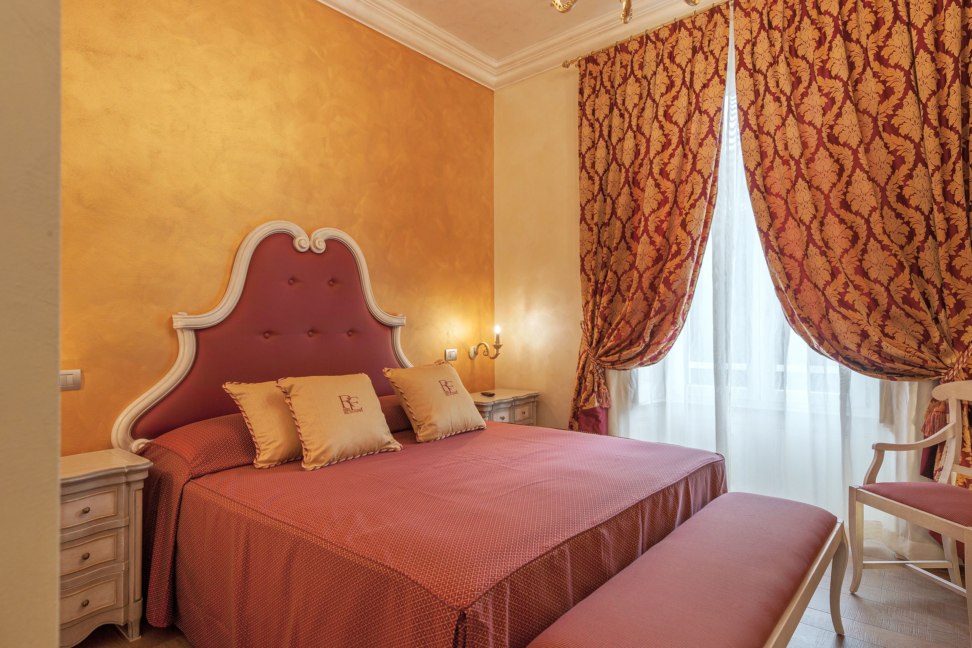 Une chambre avec un grand lit, deux tables de chevet et une chaise.