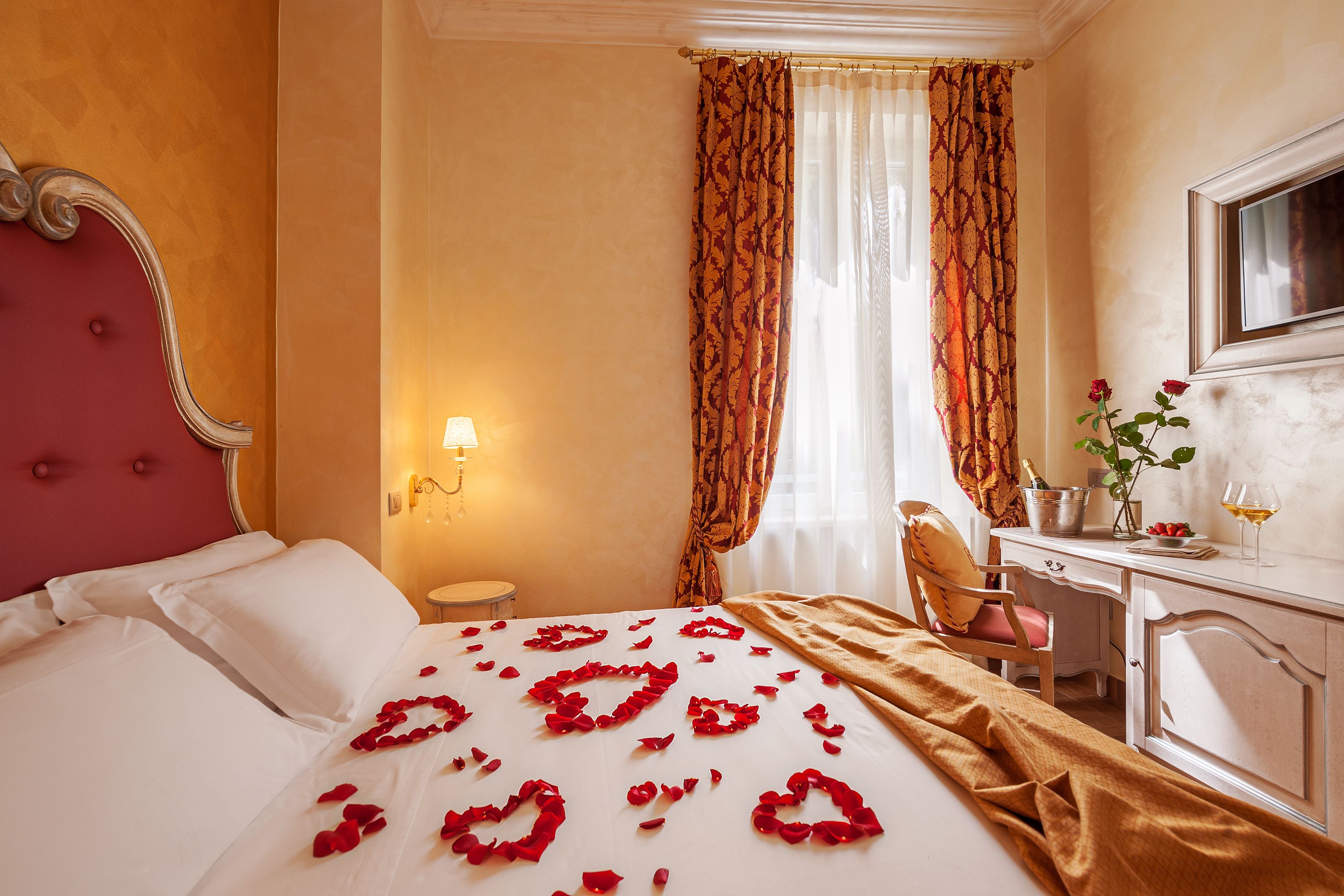 A hotel room with a bed, a desk, a chair, and a window with curtains.