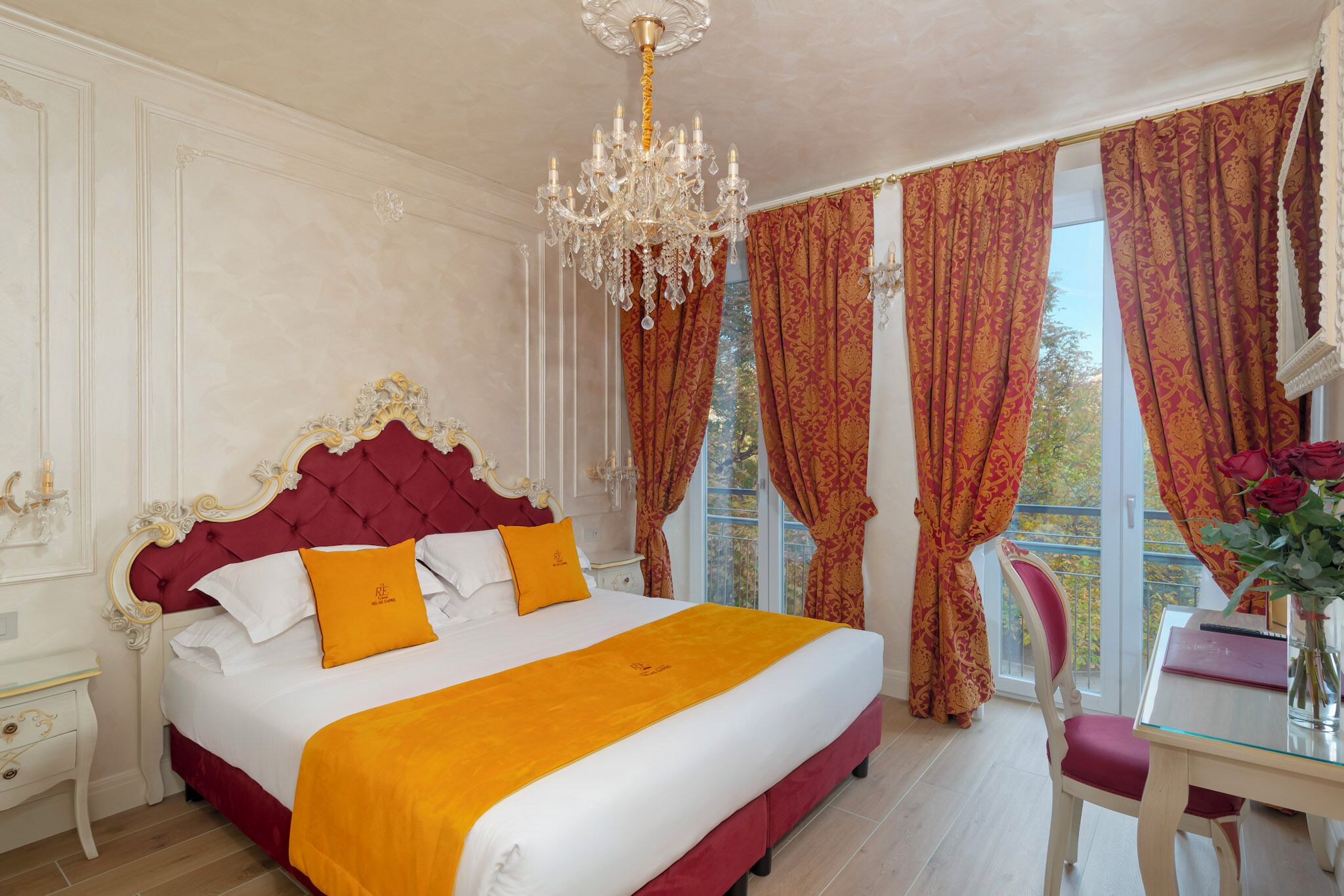A luxurious bedroom with a large bed, ornate headboard, and a chandelier.