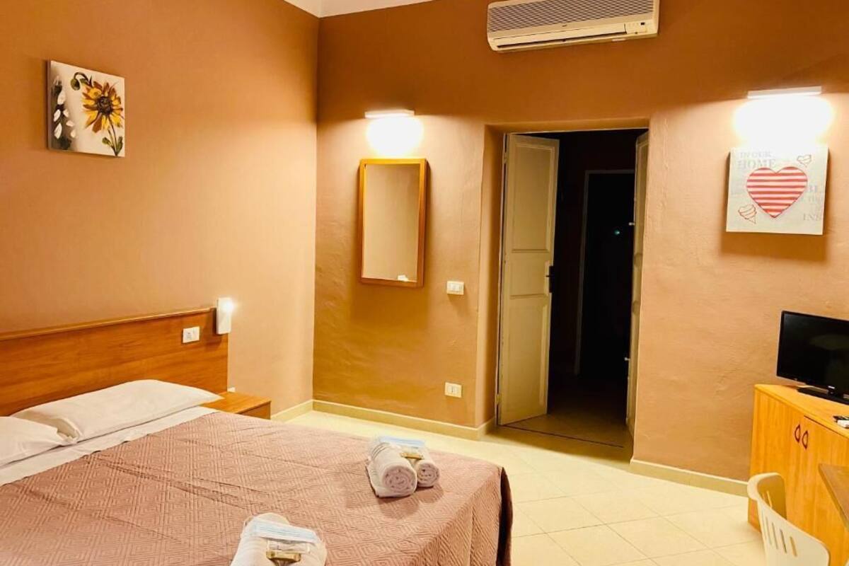 Ein Hotelzimmer mit Bett, Nachttisch, Fernseher und einer Badezimmertür.