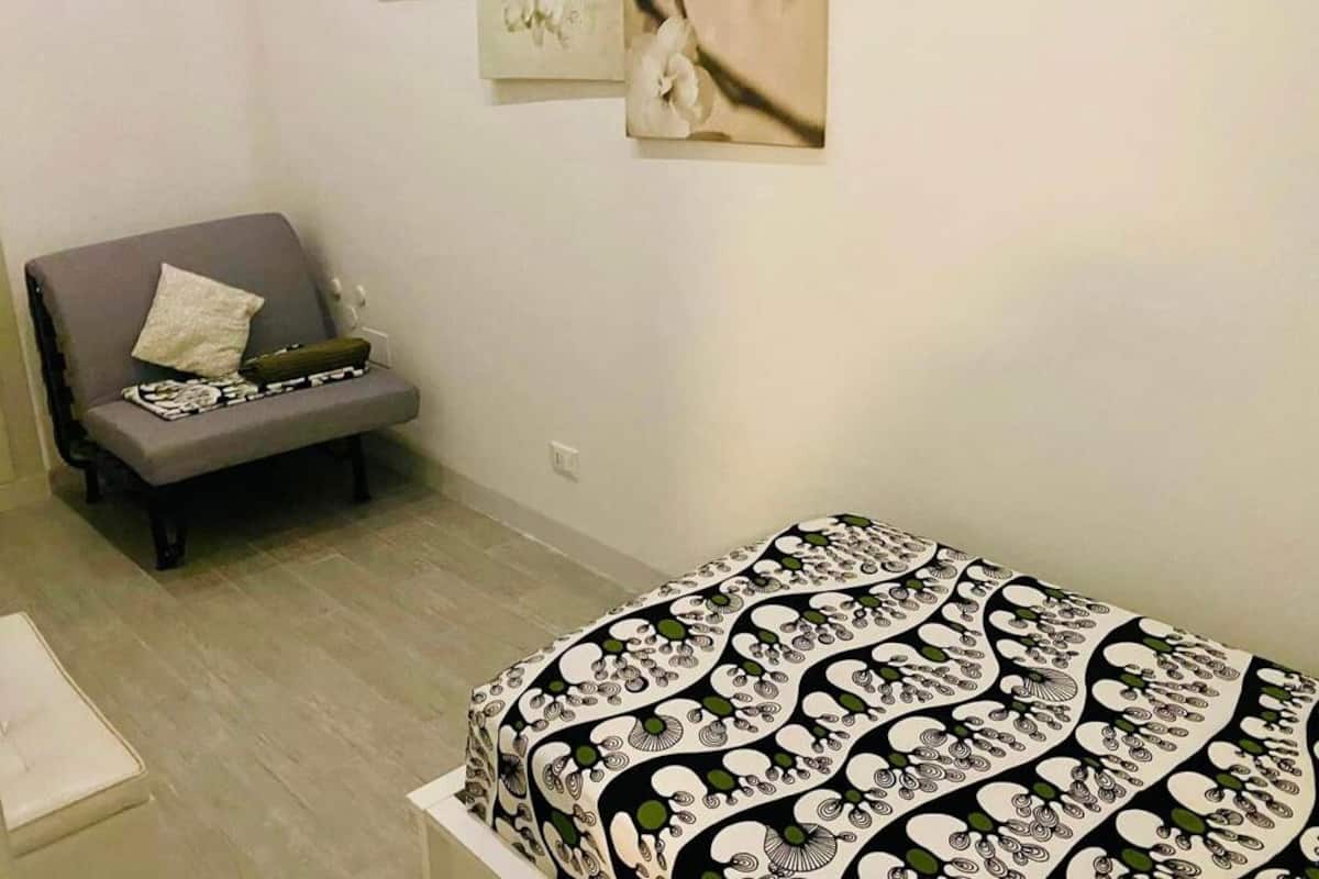 Ein Zimmer mit einem Bett, einem grauen Sofa und Wandbildern.