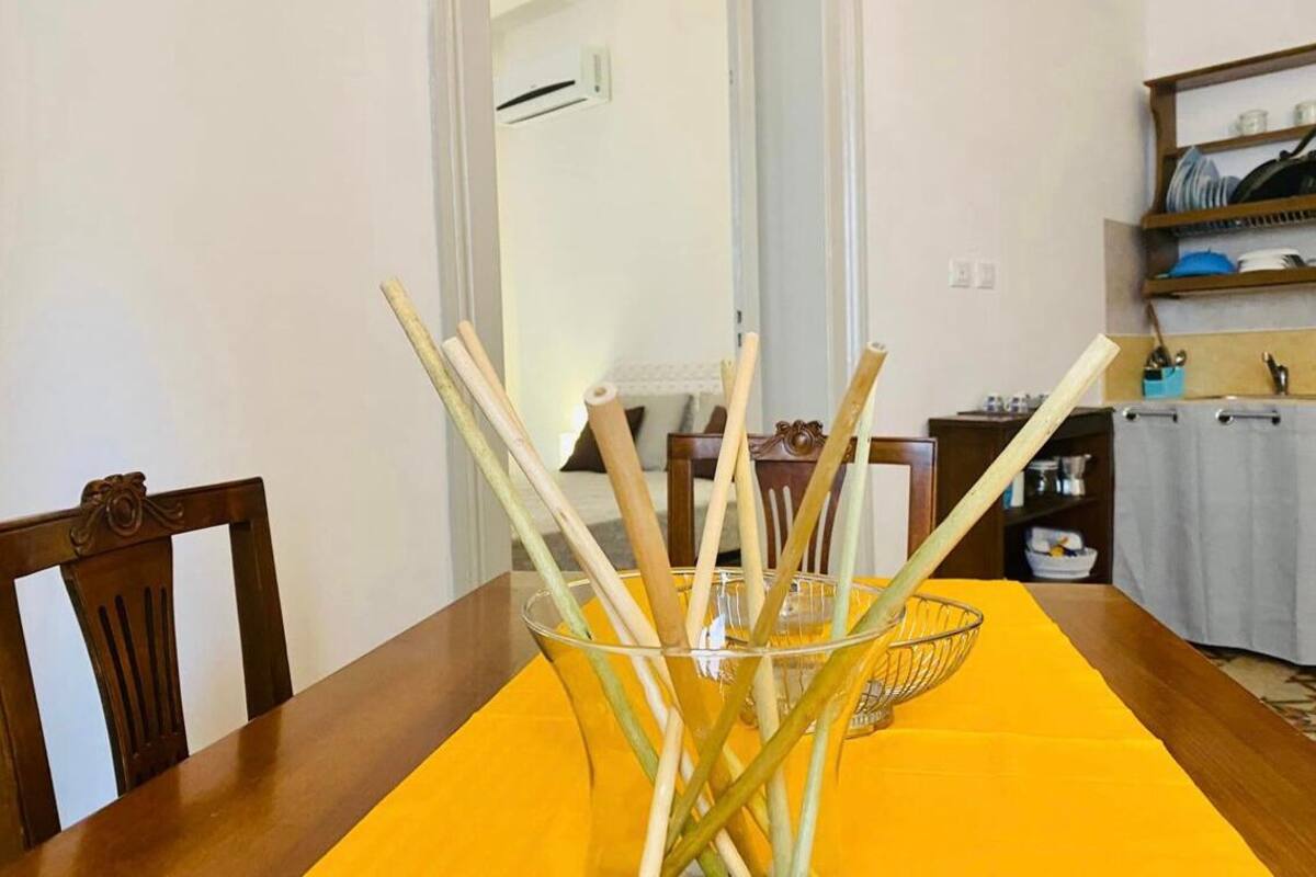 Ein Esstisch mit einer gelben Tischdecke und einer Glaskugel mit Holzstielen.