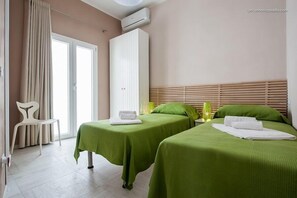 Een hotelkamer met twee bedden, een stoel, een kledingkast en een raam met gordijnen.