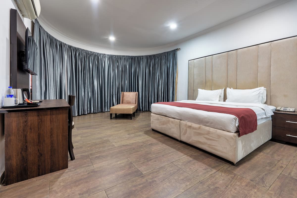 Ein Hotelzimmer mit einem großen Bett, einem Holztisch, einem Stuhl und einem an der Wand montierten Fernseher.