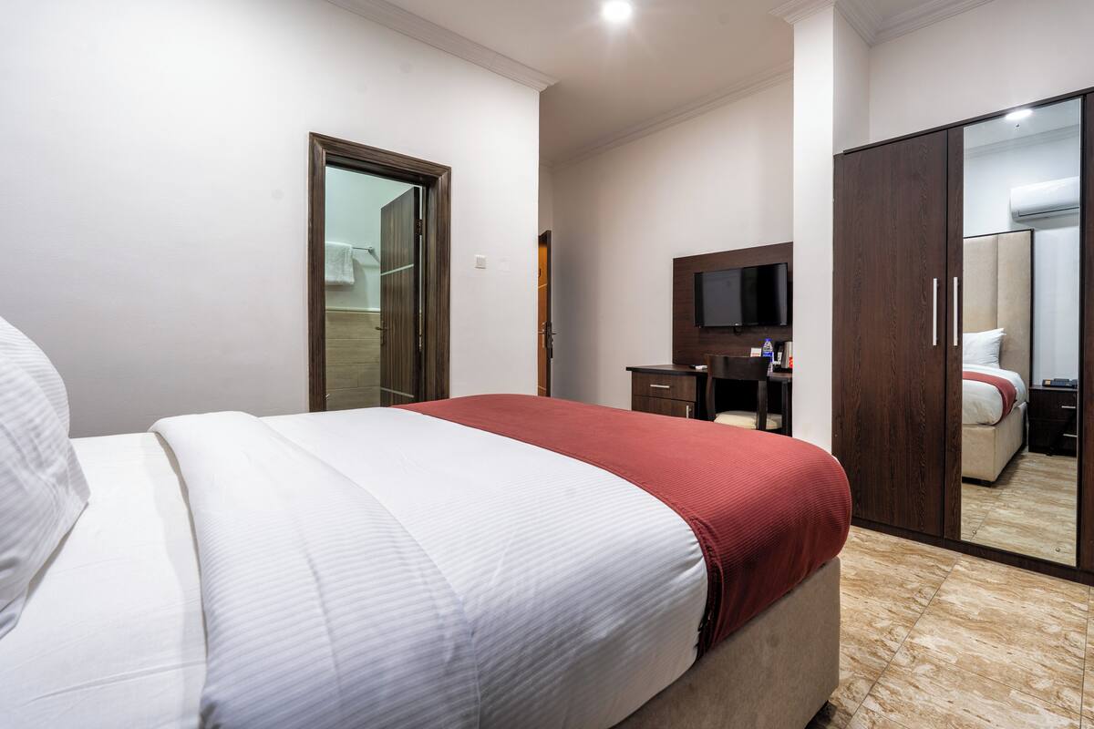 Ein Hotelzimmer mit Bett, Schreibtisch, Fernseher und Kleiderschrank.