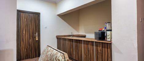 Una habitación con un armario de madera, un sofá estampado con motivos florales y un estante empotrado para microondas.