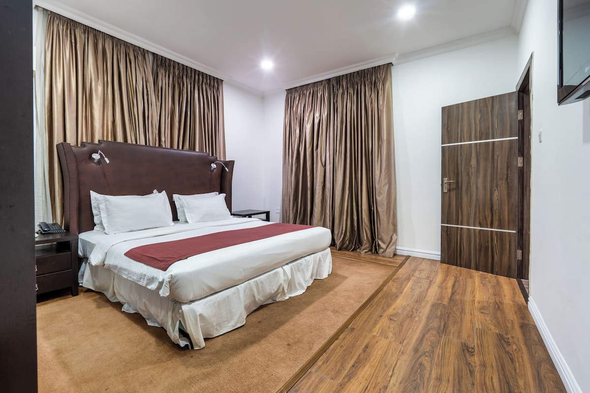 Ein Schlafzimmer mit einem großen Bett, Holzboden und Vorhängen.