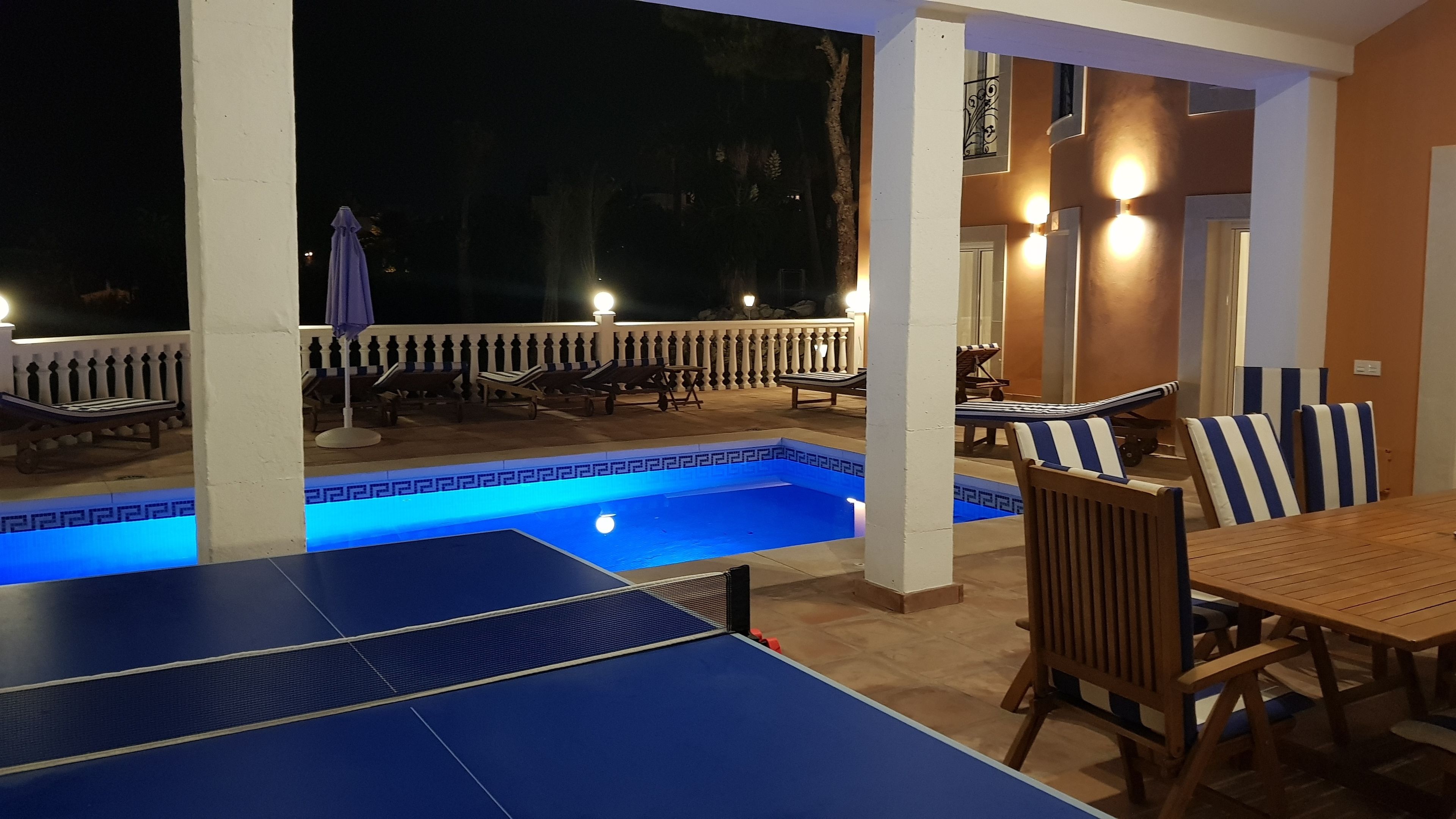 Un espace piscine extérieur avec des chaises longues et une table de ping-pong.
