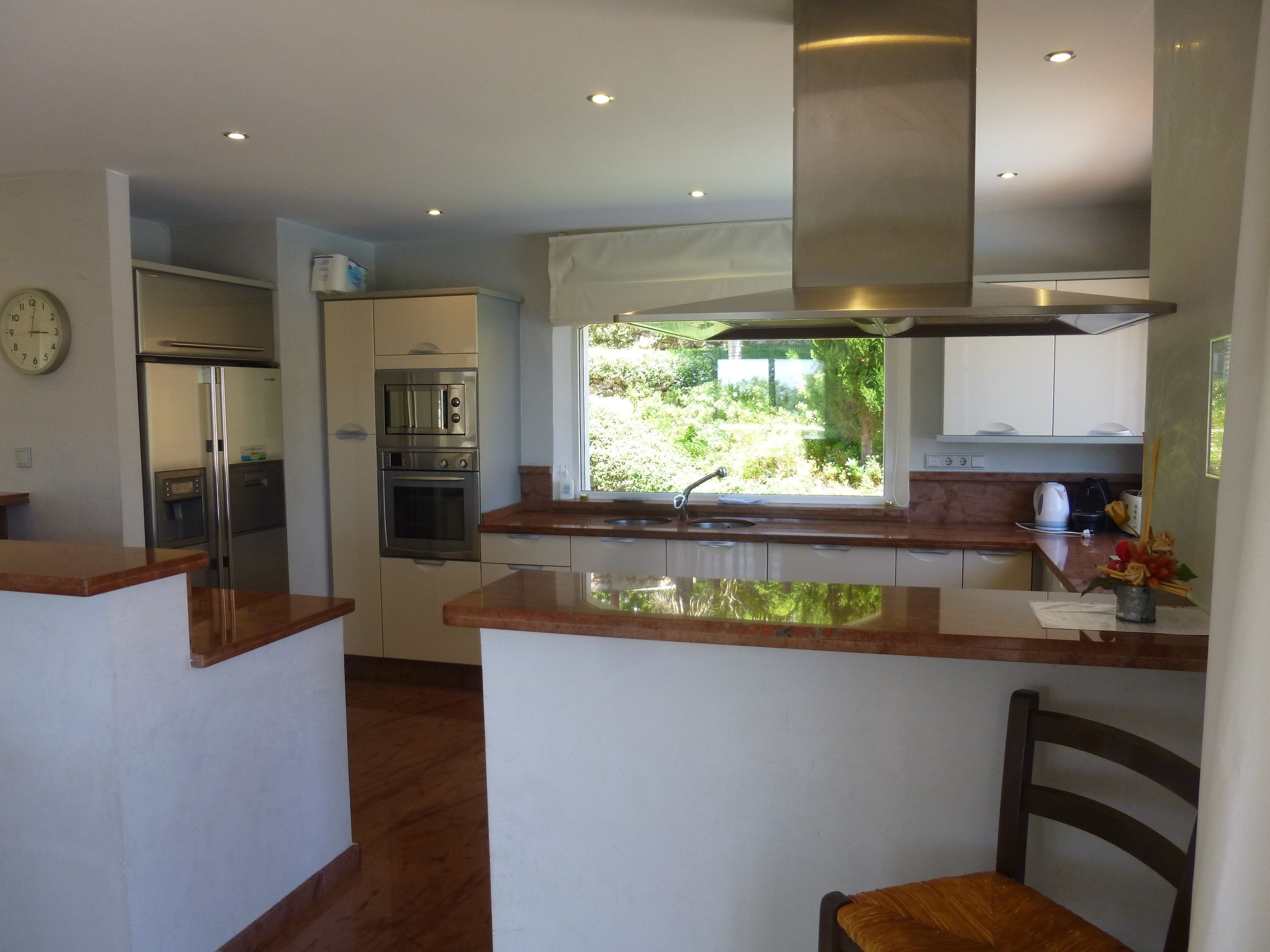 Una cocina moderna con electrodomésticos de acero inoxidable, un ventanal grande y una isla de madera.
