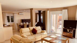 A modern living room with a beige sofa, a glass-top coffee table, and a flat-screen TV. - La Perla de Torrenueva (Mijas)