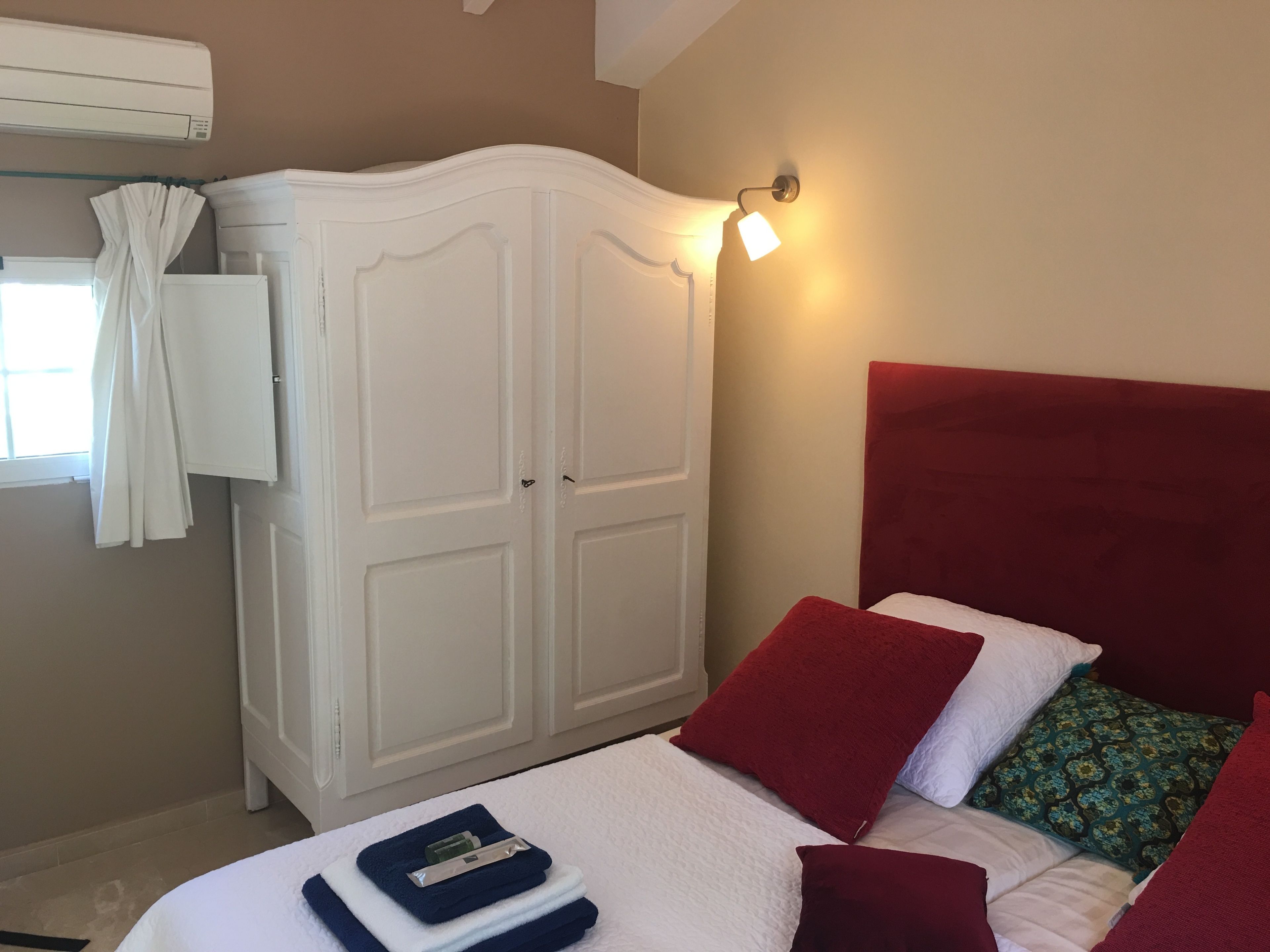A hotel room with a bed, a wardrobe, and a window with curtains.