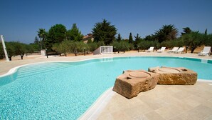 A clear swimming pool with two stone steps leading into it, surrounded by lounge chairs and trees. - Casale la Macina Hotel & Residence (Castellammare del Golfo)