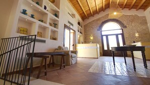 A spacious room with a high ceiling, a stone wall, and a wooden staircase. - Casale la Macina Hotel & Residence (Castellammare del Golfo)