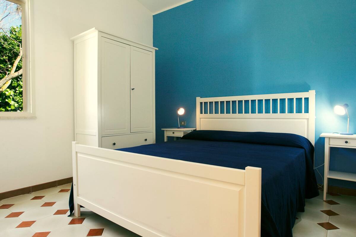 Une chambre à coucher avec un lit, une armoire blanche et deux tables de chevet avec des lampes.