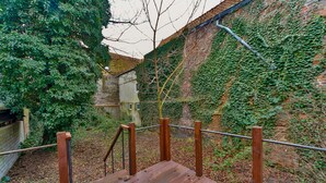 Eine Holztreppe führt zu einer Backsteinmauer mit Efeu.