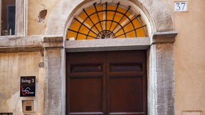 A double wooden door with a stone archway, a number 37 sign, and a 'living 3' sign on the wall. - Babuccio Art Inn (Rome)