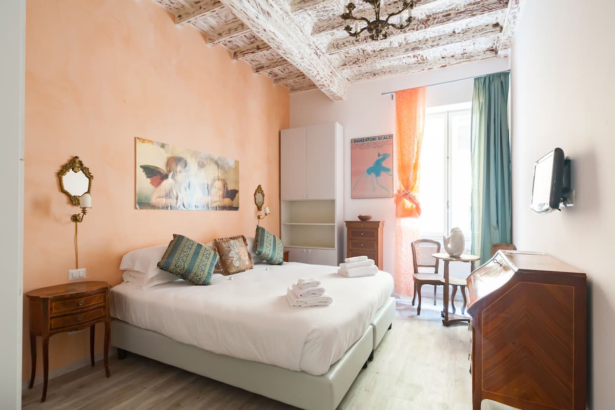 A bedroom with a bed, a nightstand, a dresser, a chair, and a desk.