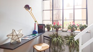 A workspace with a desk, chair, lamp, and potted plants by a window. - Babuccio Art Inn (Rome)