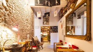 A cozy room with a rustic stone wall, wooden furniture, and a large mirror. - Babuccio Art Inn (Rome)