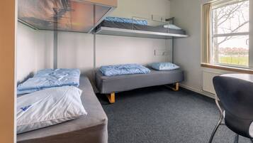 Um quarto de dormitório com beliches, uma escrivaninha e uma cadeira.