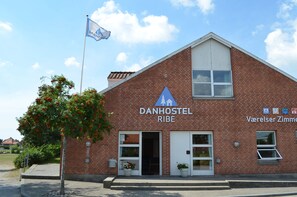 A brick building with a sign reading "DANHOSTEL RIBE" and "Varelser Zimmer".