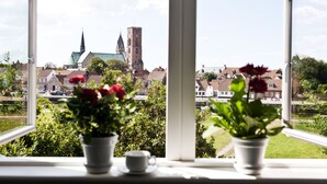 A view through a window with potted plants and a cup on the windowsill.