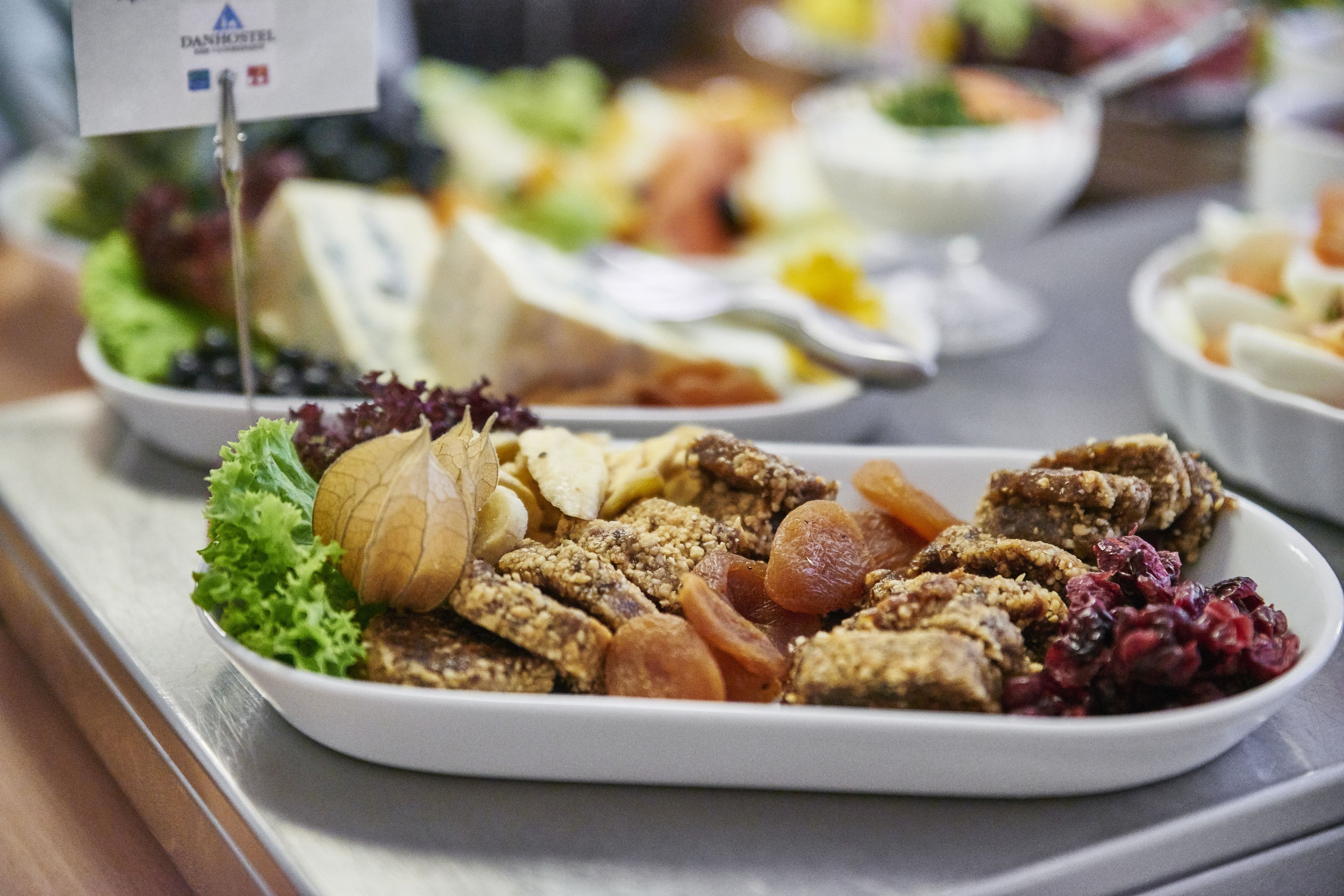 Una mesa de buffet con diversos alimentos, entre ellos frutas, frutos secos y una bandeja de quesos.