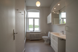A modern bathroom with a toilet, sink, and mirror. - Det Gamle Rådhus (Grasten)