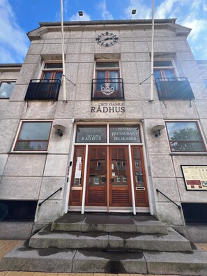 Ein Gebäude mit einer Uhr, einem Schild mit der Aufschrift 'Det Gamle Radhus' sowie Schildern für ein Hotel und ein Restaurant.