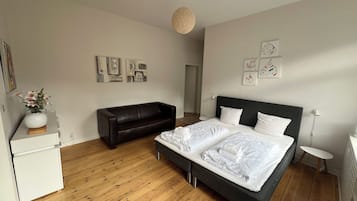 Ein Schlafzimmer mit einem Bett, einem Schlafsofa, einem kleinen Tisch und einer Wand mit Kunstwerken.